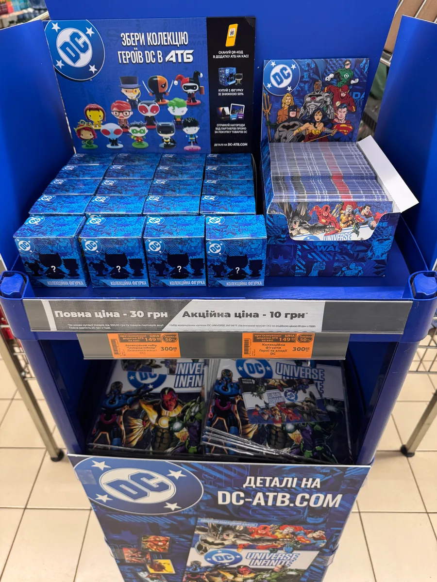 Верх стійки DC в АТБ: коробки фігурок, паки й цінники 300 і 149,99 грн